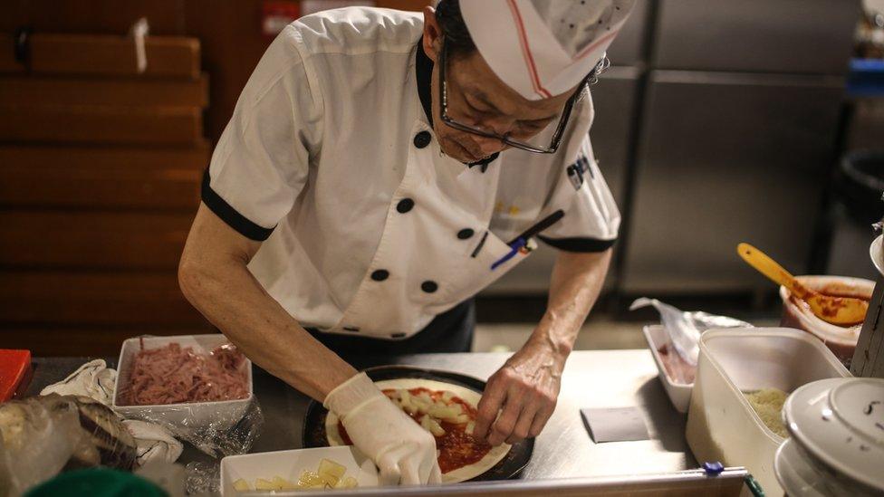 Elderly chef making a pizza