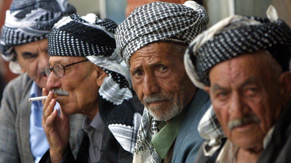 Kurdish men sit in the bazaar in Sulaimaniya, Iraq (17 October 2002)