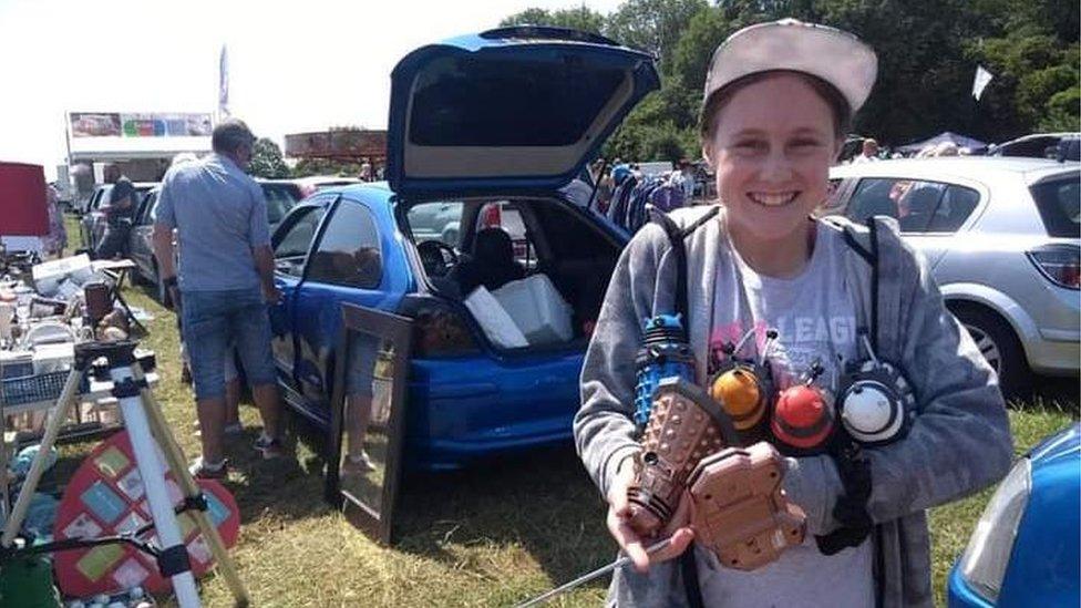 Lily Connors holding Daleks at a car boot sale