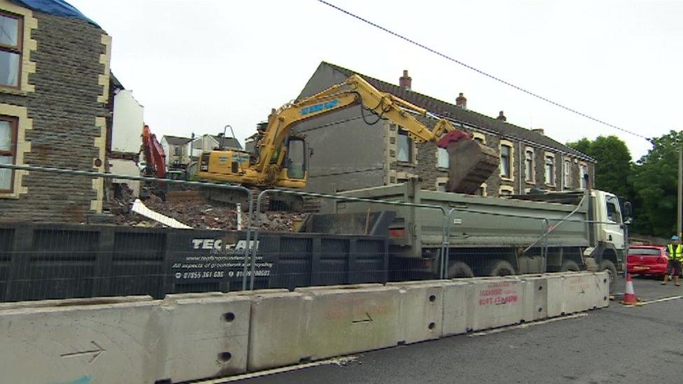 A digger clearing rubble where the family's house used to stand