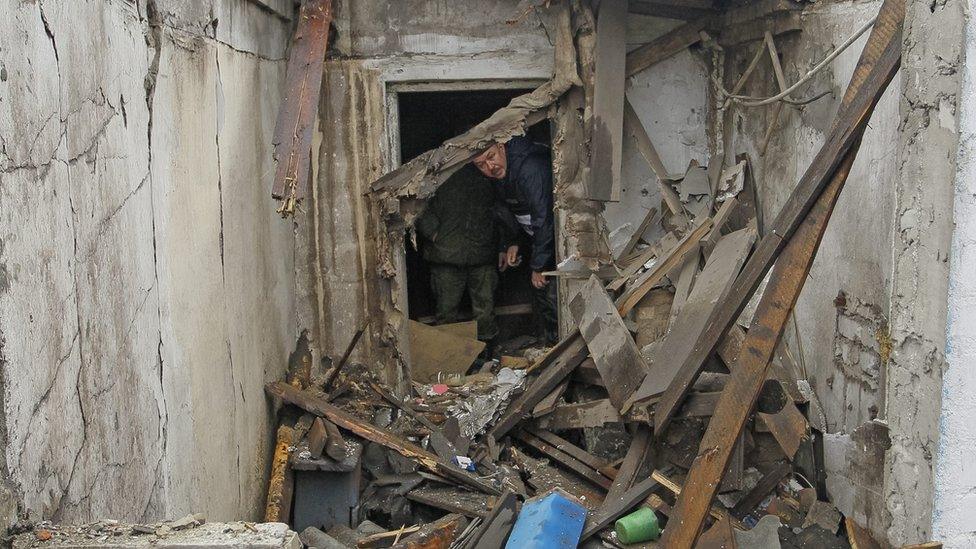 An OSCE official inspects damage caused by shelling in Ukraine