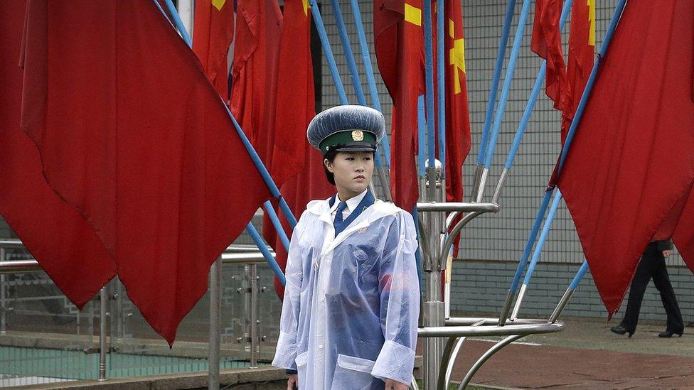 A North Korean traffic woman stand in front of flags