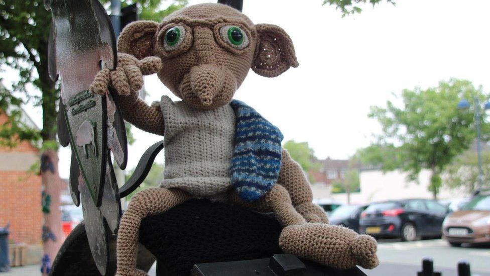 A knitted version of Dobby perched on a post box