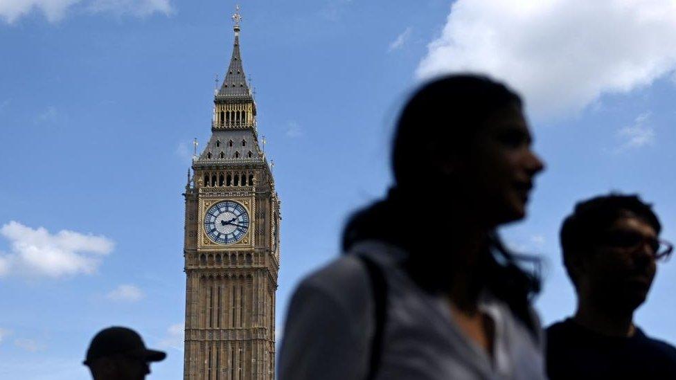 People walk by Houses of Parliament in London, Britain