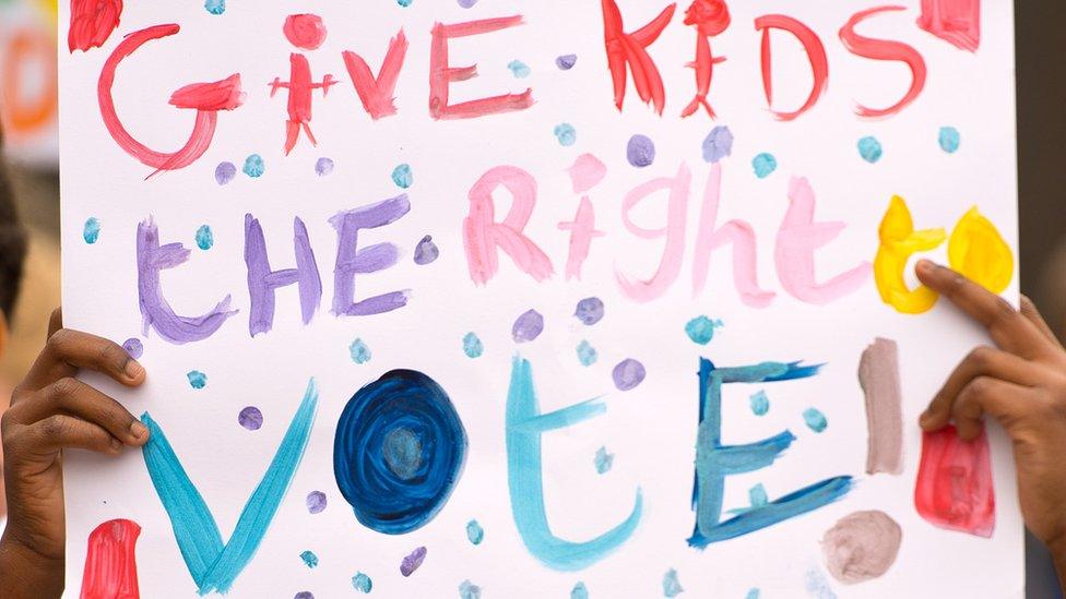 A placard saying "give kids the right to vote"