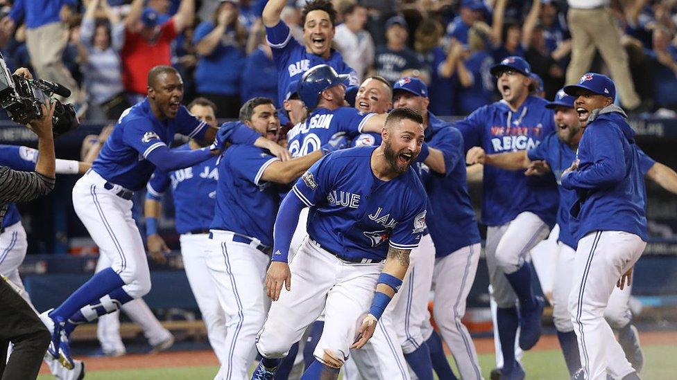 Josh Donaldson #20 of the Toronto Blue Jays is congratulated by Troy Tulowitzki #2 after scoring the game-winning run as Kevin Pillar #11 runs while celebrating in the tenth inning during MLB game action against the Texas Rangers in game three of the American League Division Series at Rogers Centre on October 9, 2016 in Toronto, Canada.