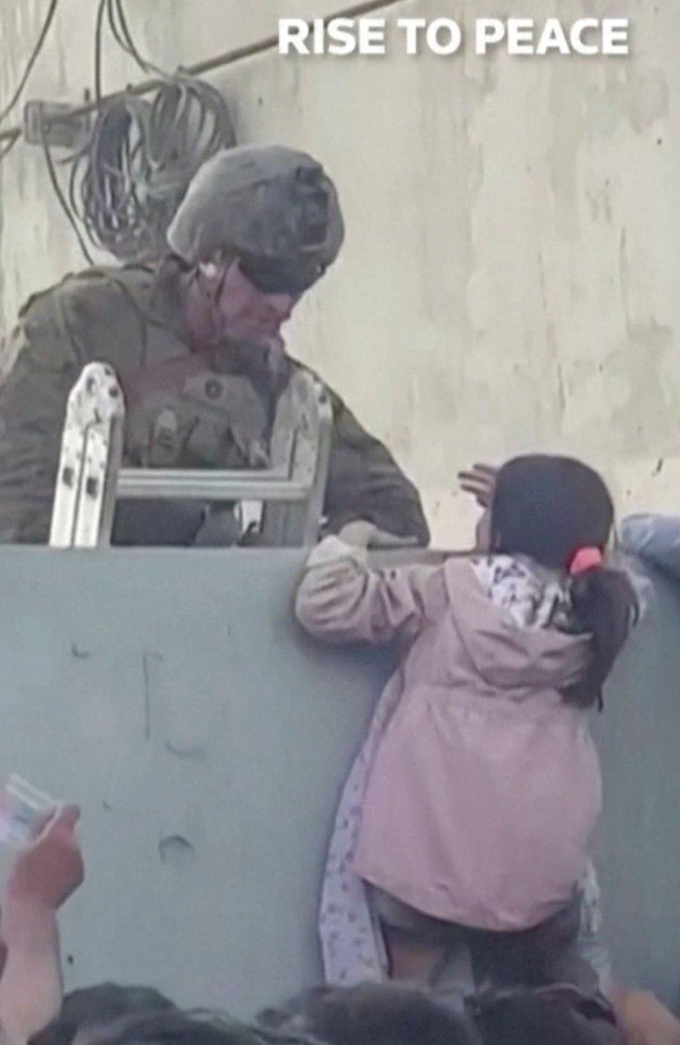 A girl is helped over a wall at Kabul airport