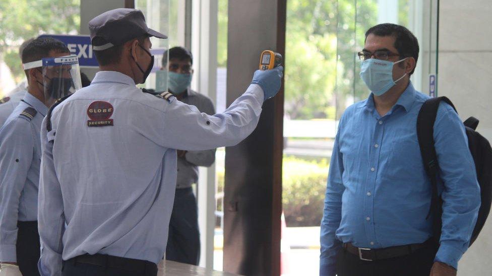 A security guard thermal screens people as they enter an office building at Park Centra in Sector 30, on June 8, 2020 in Gurugram, India.