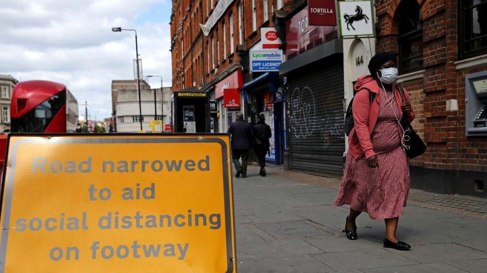 Woman walking on High Street wearing face mask