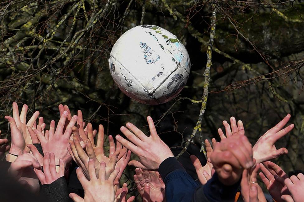 Competitors from the opposing teams, the Up'ards and the Down'ards, reach for the ball during the annual Royal Shrovetide Football Match in Ashbourne, northern England. 25 February 2020