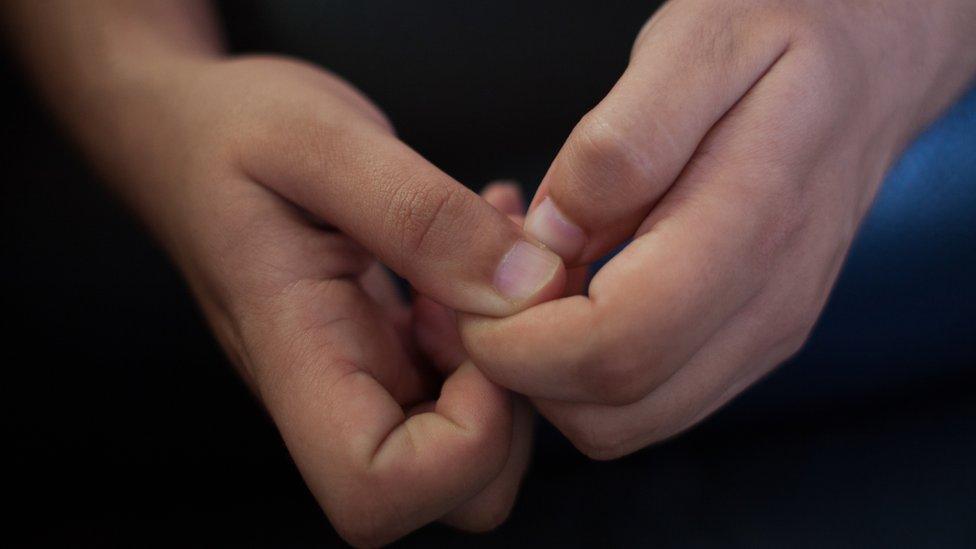 Close-up, teenage boy clasps hands