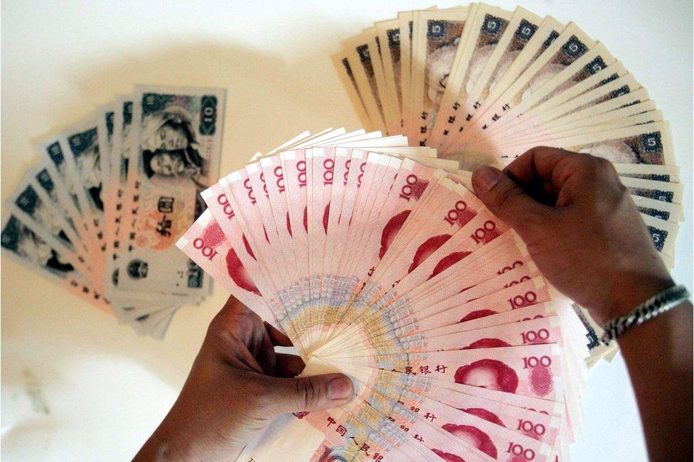 A man lays out the various denominations of the Chinese yuan, in Beijing 8 June 2005.