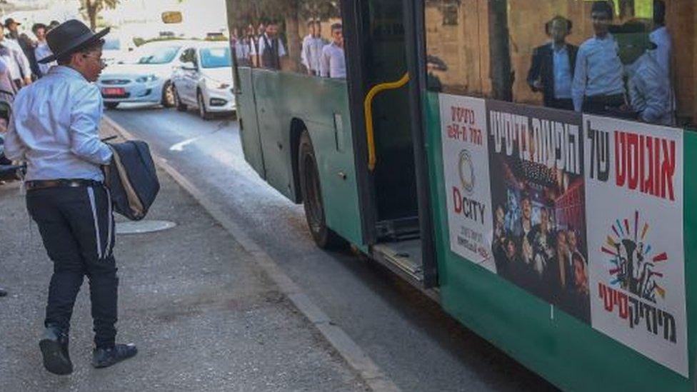 An Israeli passer-by looks at a bus