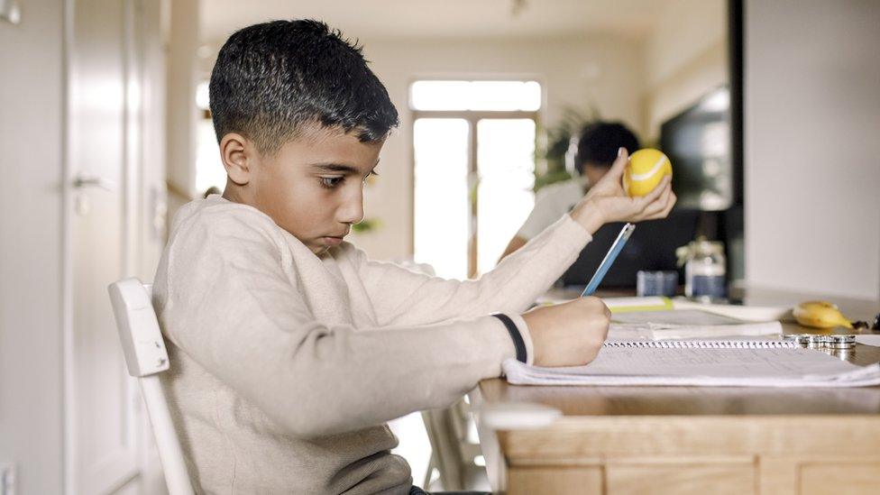 Boy learning while writing in book at home