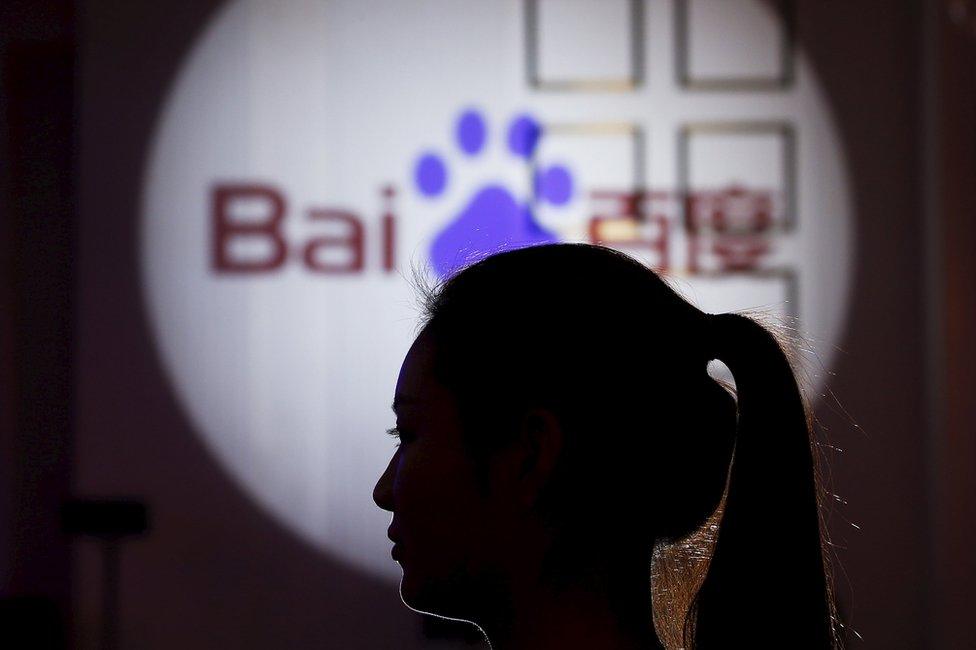 A woman is silhouetted against the Baidu logo at a new product launch from Baidu, in Shanghai, China, 26 November 2015