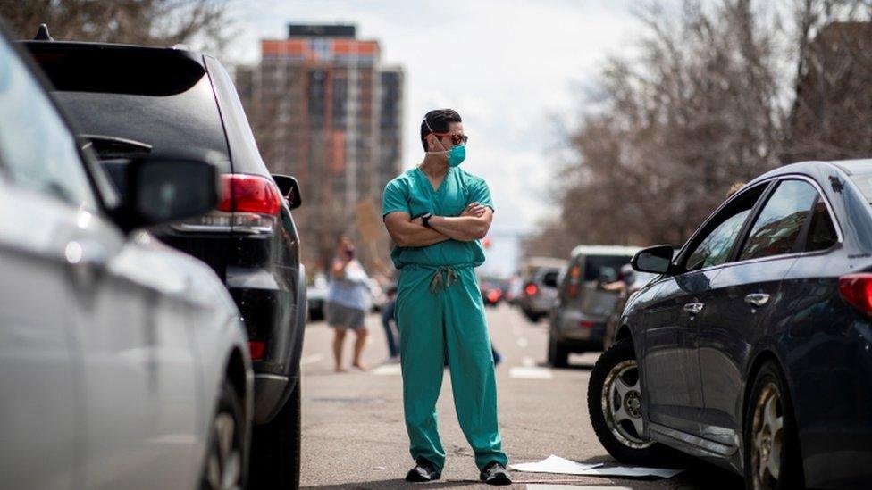 Protests against virus shutdowns in Denver on 19, April meet two counter-protesters dressed as healthcare workers