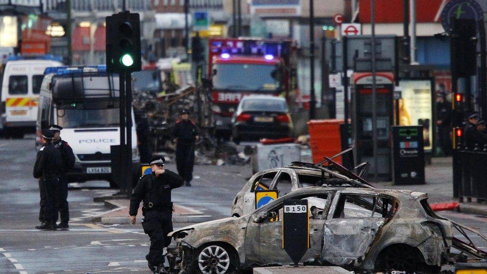 Police officers investigate after riots in Tottenham in north London