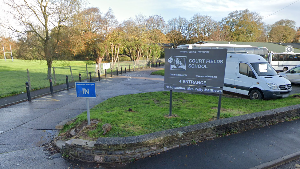 grey school sign at an entrance