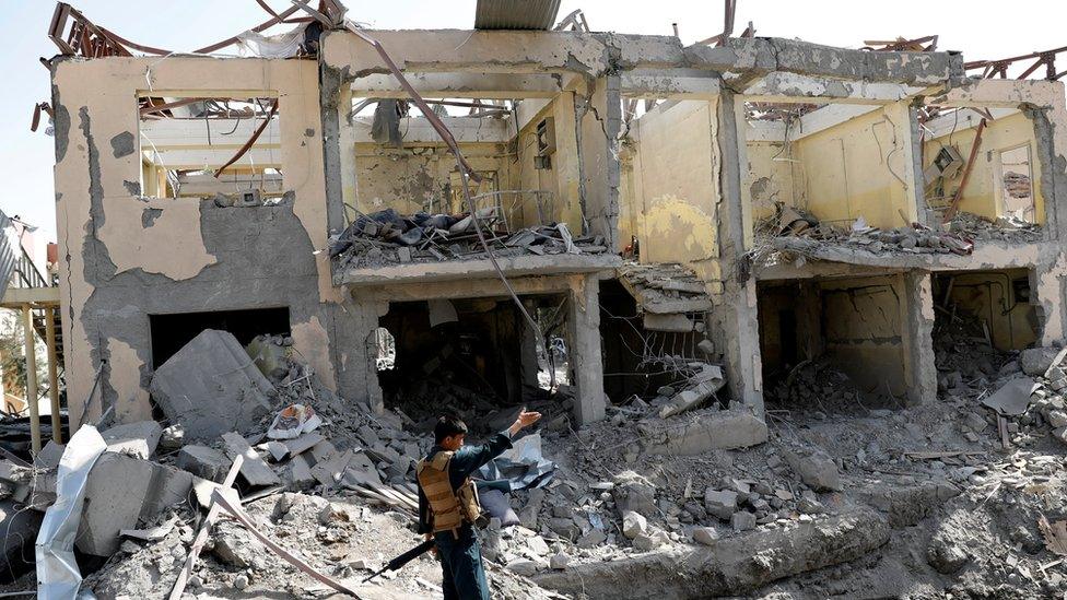 An Afghan security officer stands guard at the site of a bomb blast on 7 August in Kabul, where a building stands hollowed out