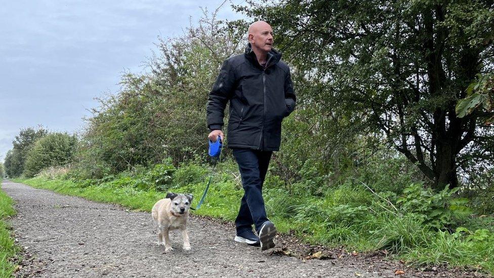 A man walking his dog in the countryside