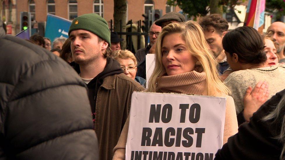 A woman holds up a 'No to racist intimidation sign'