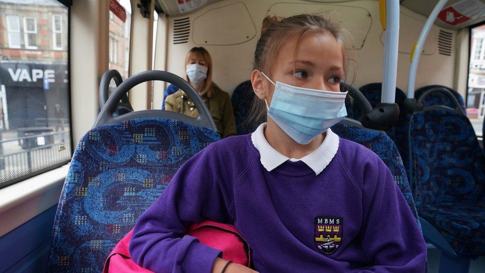 Schoolgirl on a bus wearing a facemask