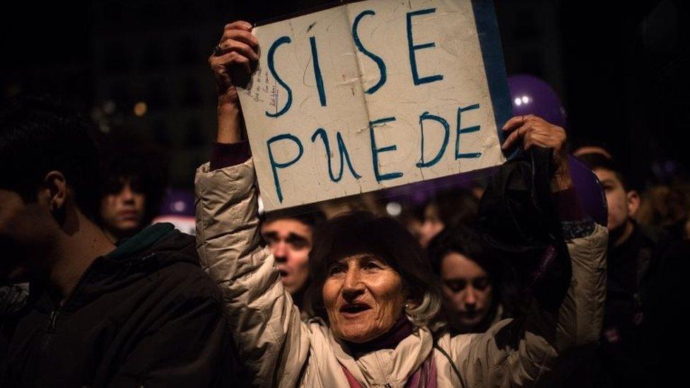 A Podemos supporter holds up a banner that it reads "Si se Puede" (Yes, we can")