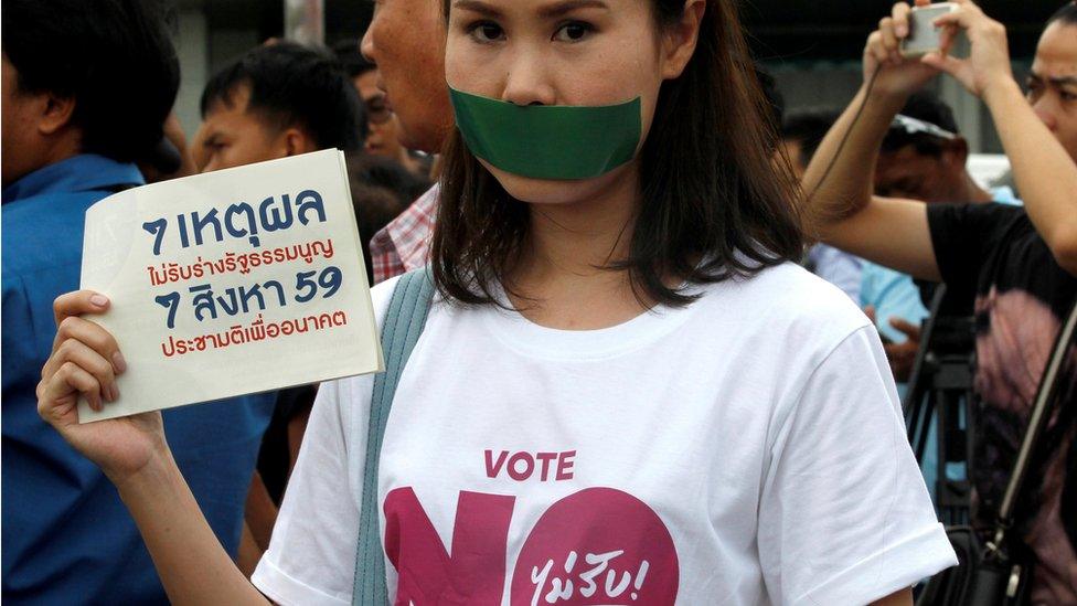 An activist holds a placard reading "7 Reasons To Not Accept Constitution"