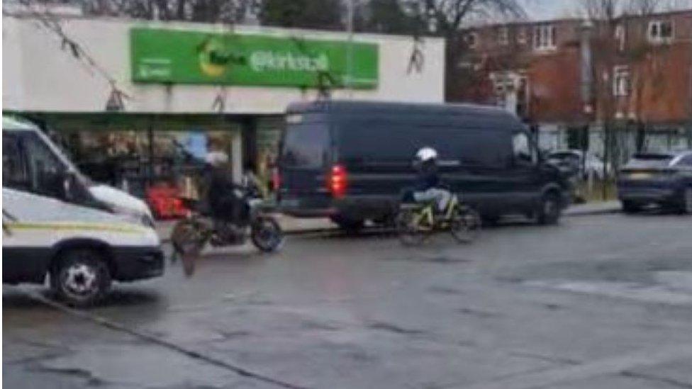 Still of two suspects riding away on bikes