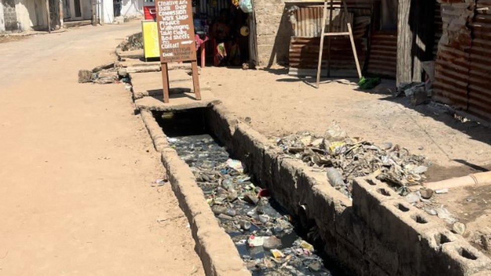 A body of water in the village with rubbish in