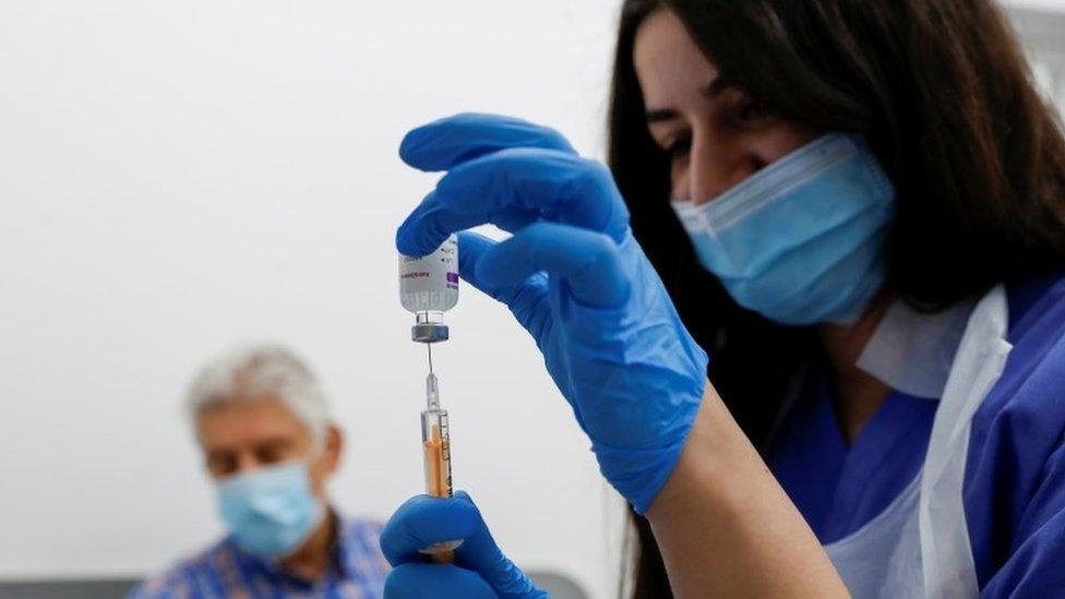 A health worker fills a syringe with a dose of the Oxford/AstraZeneca COVID-19 vaccine at Cullimore Chemist in Edgware, London