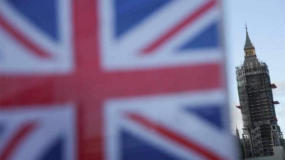 A Union Flag is seen with Elizabeth Tower (Big Ben) shrouded in scaffolding in the background