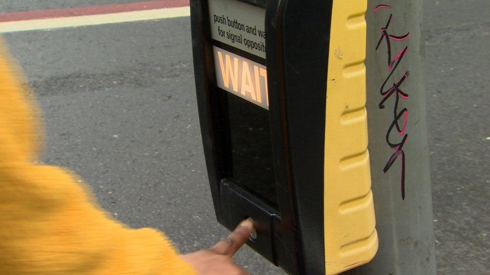 Man pressing a wait button at traffic lights