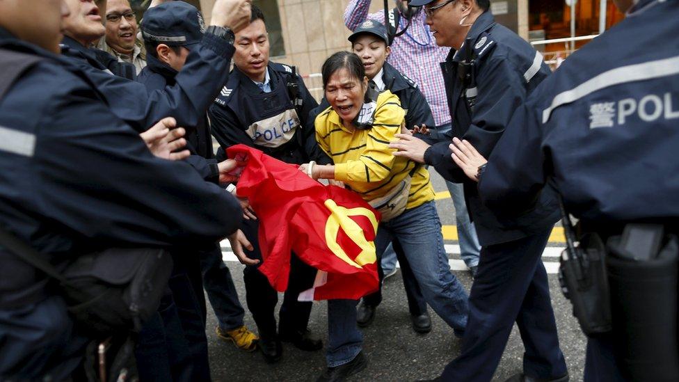 A woman protesting the disappearance of Hong Kong booksellers clutches a Chinese flag