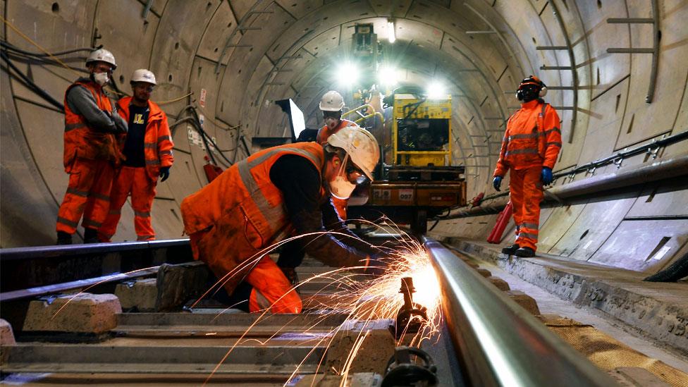 Construction workers work on a section of train track inside a Crossrail tunnel, beneath Stepney in east London in 2016