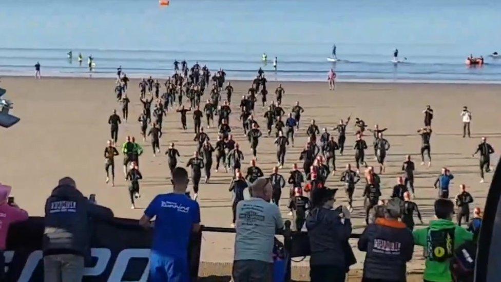 Athletes run into the sea at Barry