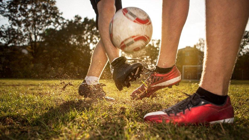 Close up of two footballers' feet doing battle for a ball