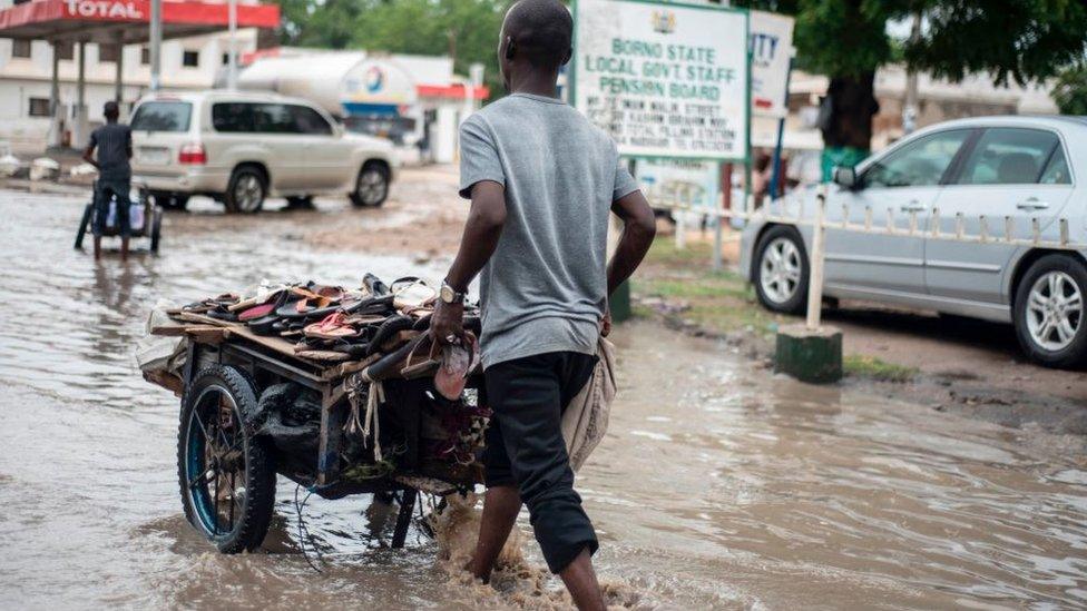 A sandal vendor pushes his cart through the flooded streets of Maiduguri in north-east Nigeria on July 5, 2017.