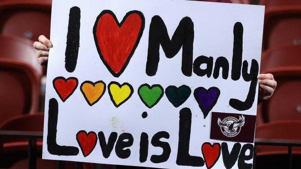 A Manly supporter holds a sign saying 'Love is Love'