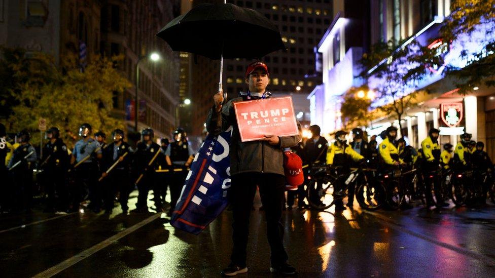 A Trump supporter leaves the rally with a police cordon nearby