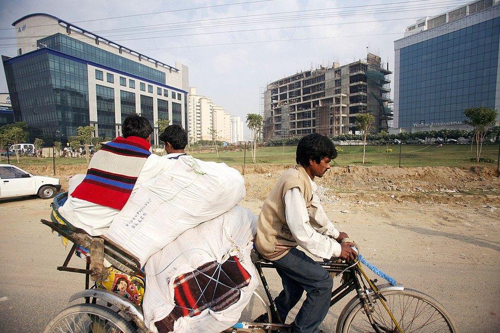 In this picture taken 06 December 2006, an Indian man pulls a cycle rickshaw past office buildings, in Gurgaon, some 30 km south of New Delhi. India's estimated 300-million-strong middle-class is not only gaining from the country's rapidly growing economy but is also driving the consumption boom. India's economy -- the second-fastest growing after China's -- grew 9.2 percent in the second quarter to September.