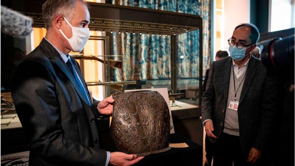 Two men looking at the chest plate of armour