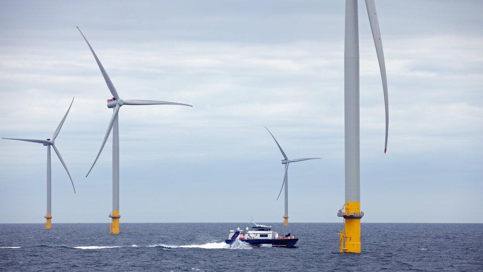 Boat approaches wind turbine at sea