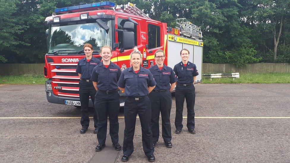 Female fire fighters standing in front of a fire engine