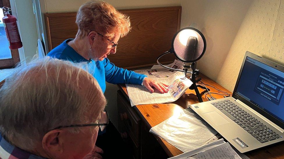 A man and woman reading the news aloud for the paper