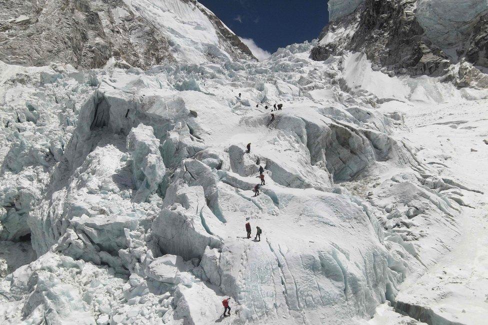 This aerial picture taken on April 18, 2021 shows climbers crossing the Khumbu icefall of Mount Everest, as seen from the Everest Base Camp, some 140 km northeast of Kathmandu