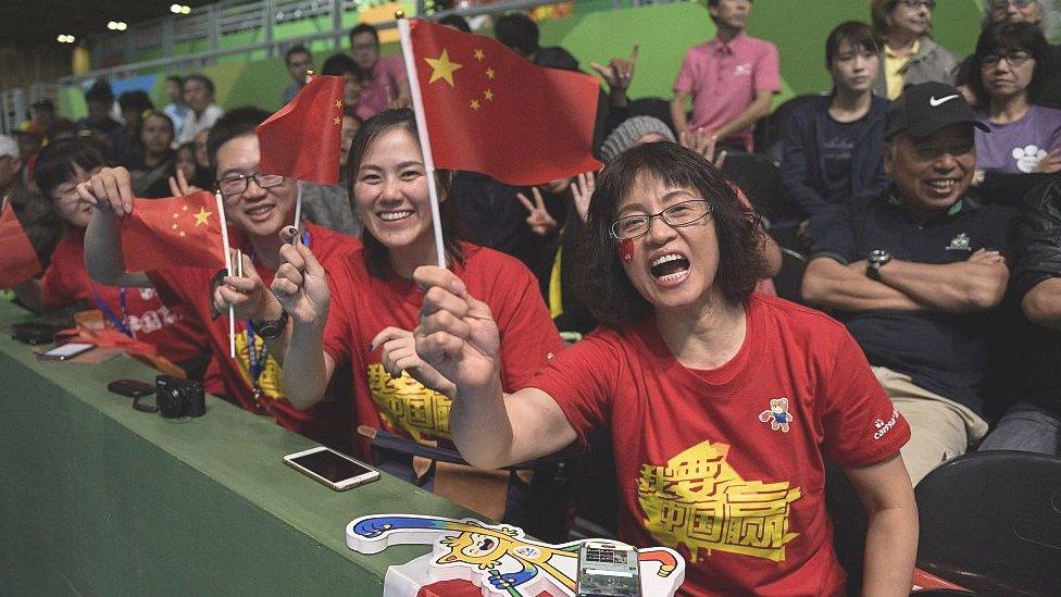 Fans of China's Li Xiaoxia cheer during her women's singles semi-final table tennis match against Japan's Ai Fukuhara