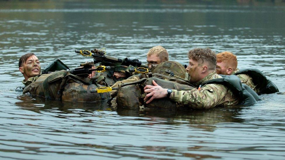 Soldiers swim across a lake on a previous march