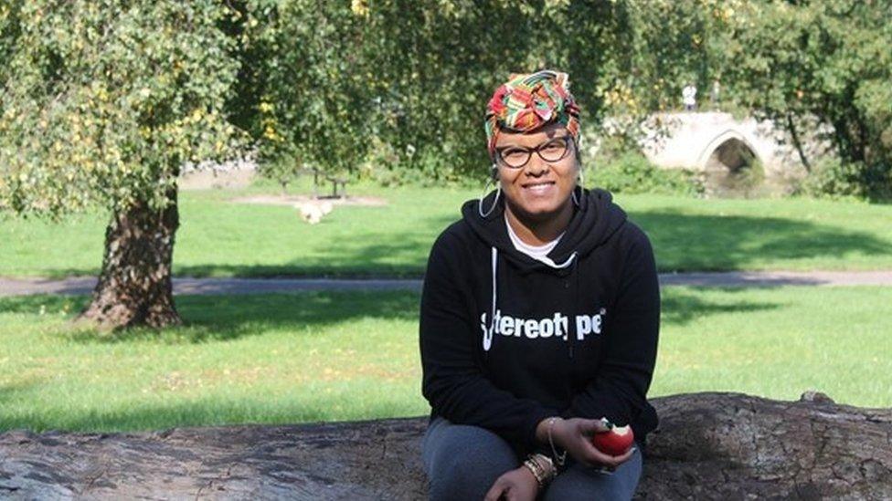 Zakiya McKenzie sitting on a log with an apple