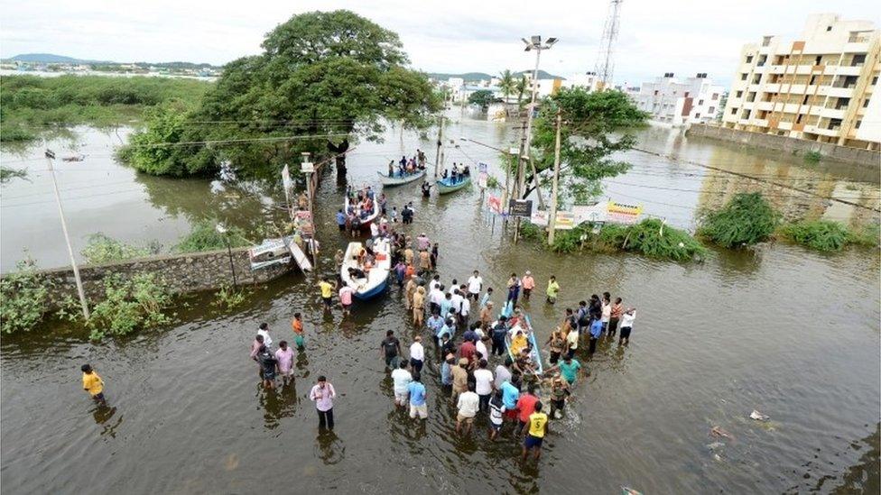 Rescue workers on a boat move people to safety at a residential area in rain-hit areas on the outskirts of Chennai on November 17, 2015